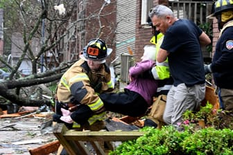 Feuerwehrleute tragen eine Frau aus ihrem zerstörten Haus: Örtliche Rettungsdienste gehen von bis zu 600 Verletzten in der betroffenen Region aus.