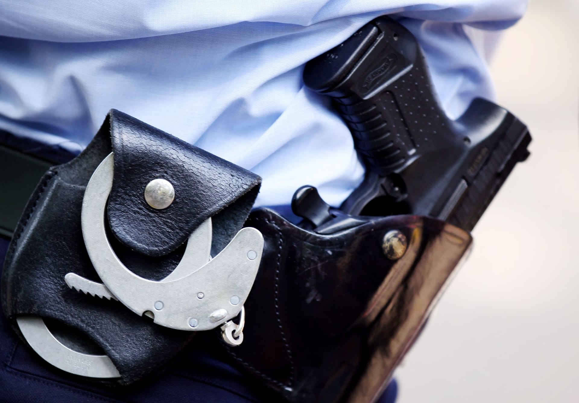 Ein Polizist mit Handschellen und Pistole am Gürtel (Symbolbild): In Hannover sind mutmaßliche Drogendealer vor der Polizei geflüchtet.