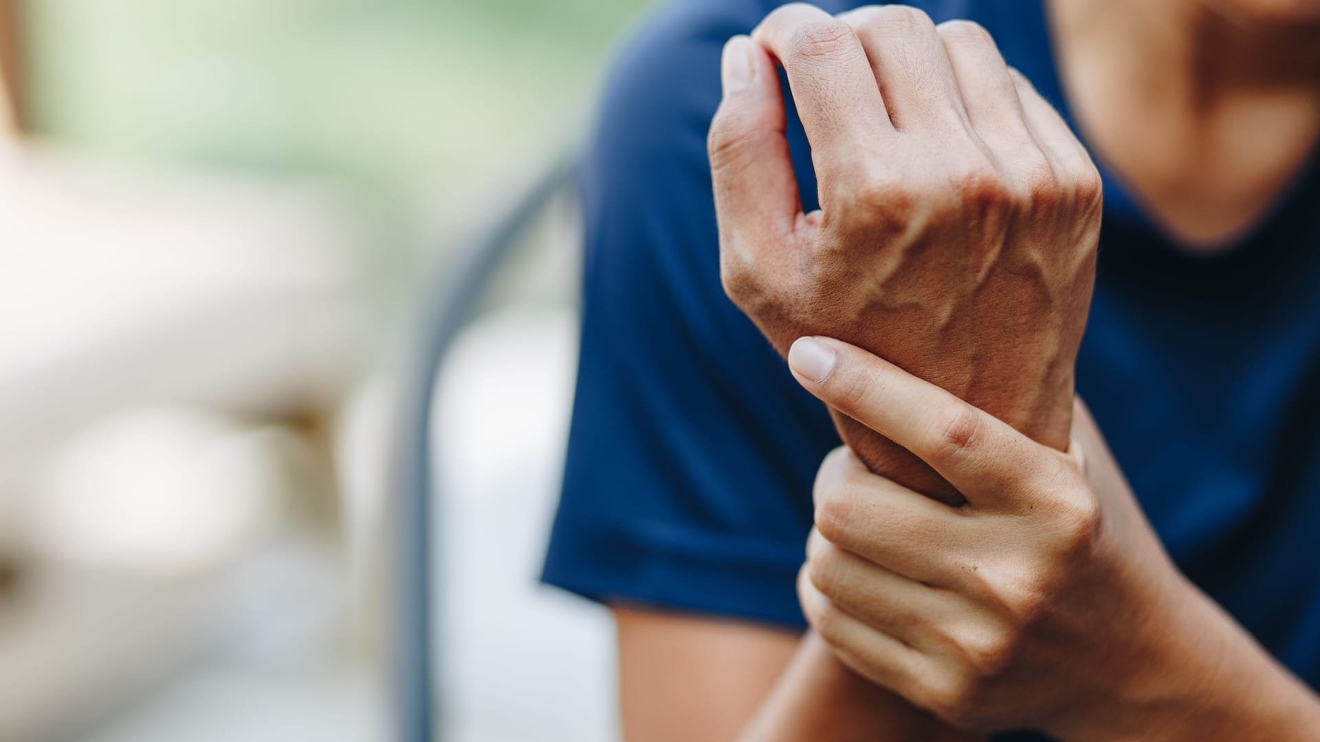 Eine Person hält sich das Handgelenk.