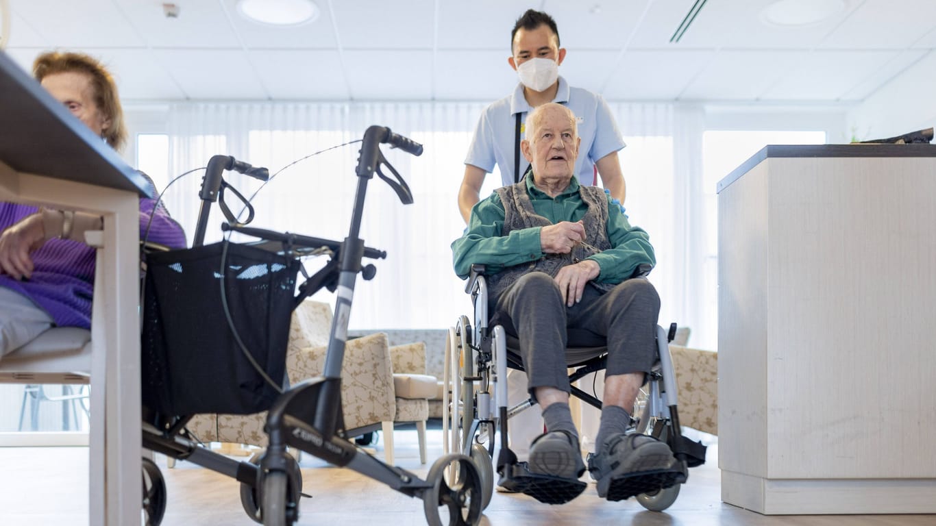 Pfleger mit Mann im Rollstuhl (Symbolfoto): Das Bundesforschungsministerium fördert das Projekt mit 16 Millionen Euro.