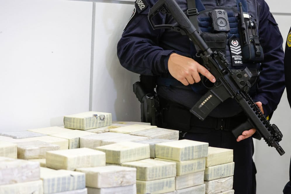 Ein Polizist bewacht die beschlagnahmten Drogenpäckchen in Queensland.