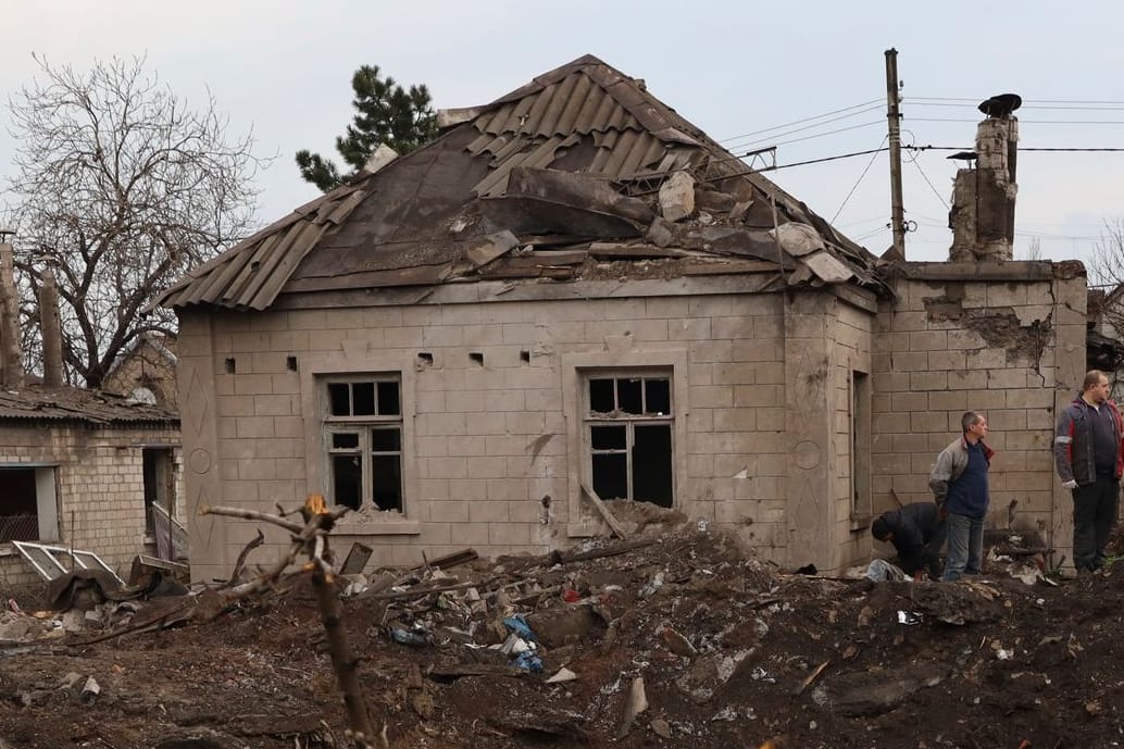 Anwohner stehen an einem von Angriffen beschädigten Haus. Bei neuen russischen Angriffen sind in der Stadt Saporischschja laut Behörden mindestens zwei Menschen gestorben.