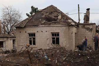 Anwohner stehen an einem von Angriffen beschädigten Haus. Bei neuen russischen Angriffen sind in der Stadt Saporischschja laut Behörden mindestens zwei Menschen gestorben.