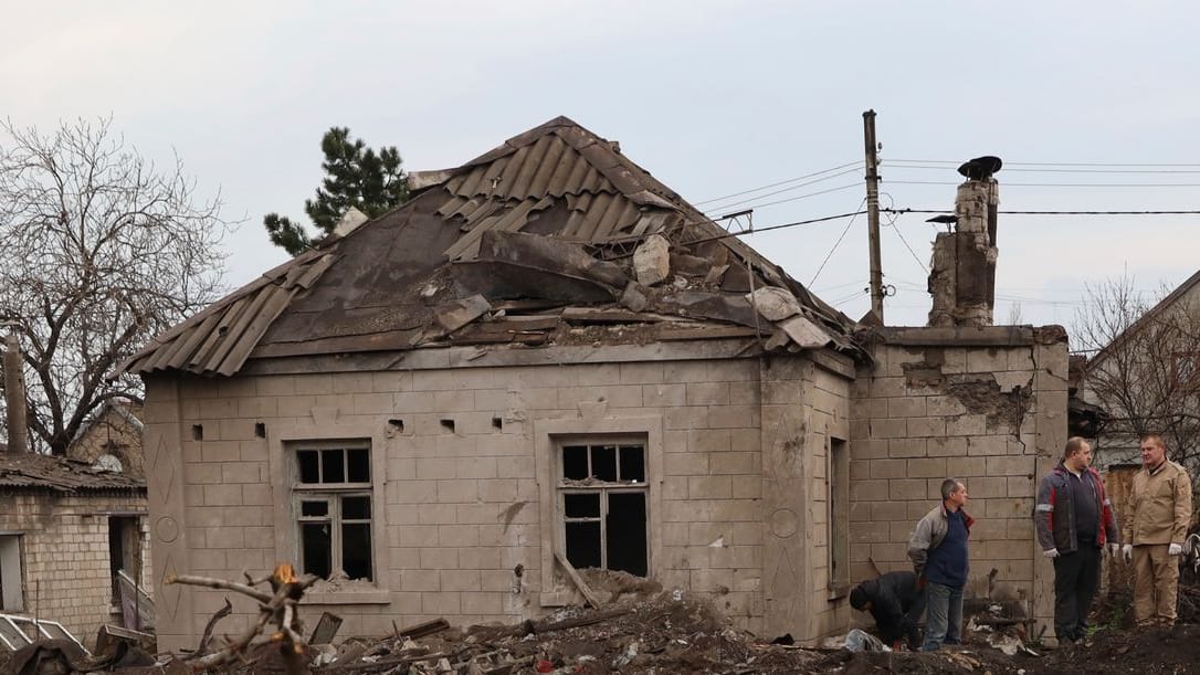 Anwohner stehen an einem von Angriffen beschädigten Haus. Bei neuen russischen Angriffen sind in der Stadt Saporischschja laut Behörden mindestens zwei Menschen gestorben.