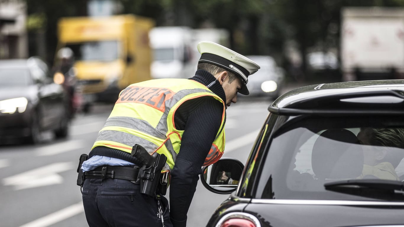 Ein Polizist kontrolliert ein Auto (Symbolbild): Die Frau hatte ihren Wagen im Halteverbot geparkt.