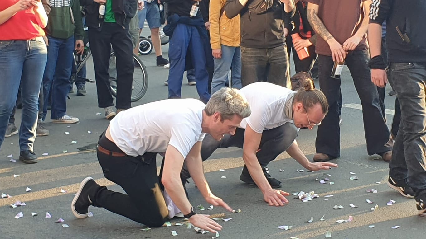 Konfetti und Geldscheine auf der Straße bei einer Demonstration in Frankfurt: Die Teilnehmer erinnern an 150 Jahre Bierkrawalle und die Probleme der lokalen Brauereien.
