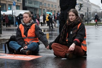 Die Sprecherinnen Lina Johnsen und Carla Rochel (rechts) von der "Letzten Generation" blockieren eine Straße in Berlin (Archivbild): Der bayerische Verfassungsschutz berichtet über Versuche von Linksextremisten sich den Aktivisten anzunähern.