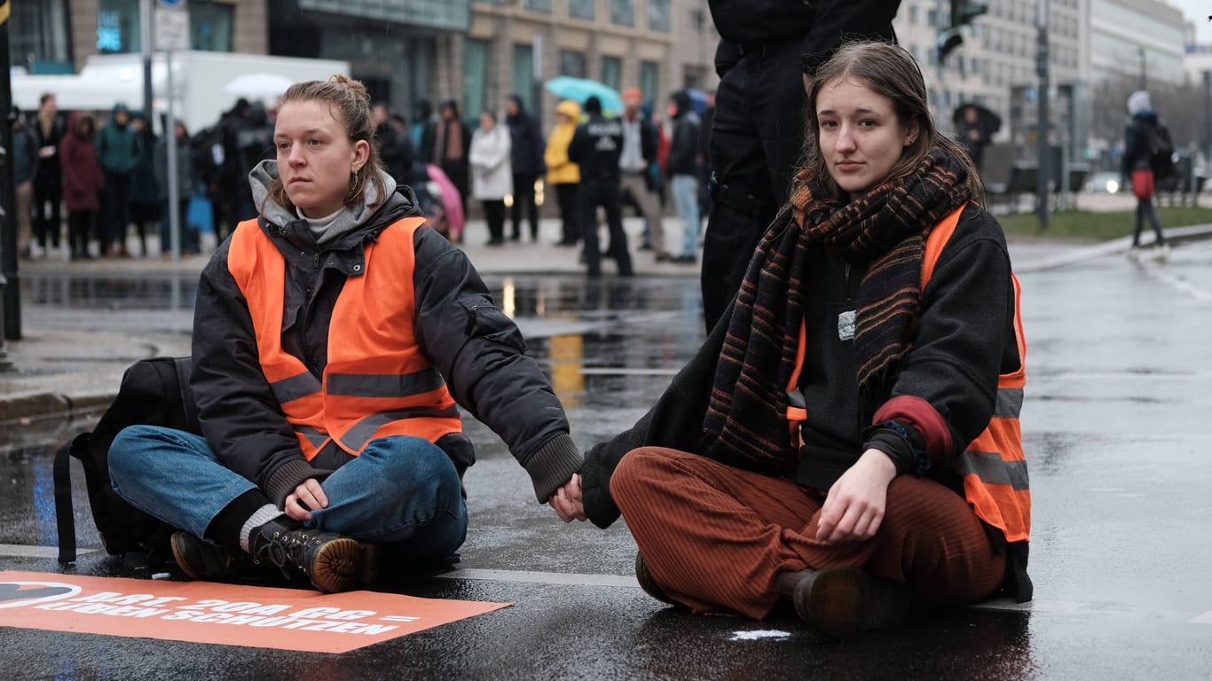 Die Sprecherinnen Lina Johnsen und Carla Rochel (rechts) von der "Letzten Generation" blockieren eine Straße in Berlin (Archivbild): Der bayerische Verfassungsschutz berichtet über Versuche von Linksextremisten sich den Aktivisten anzunähern.