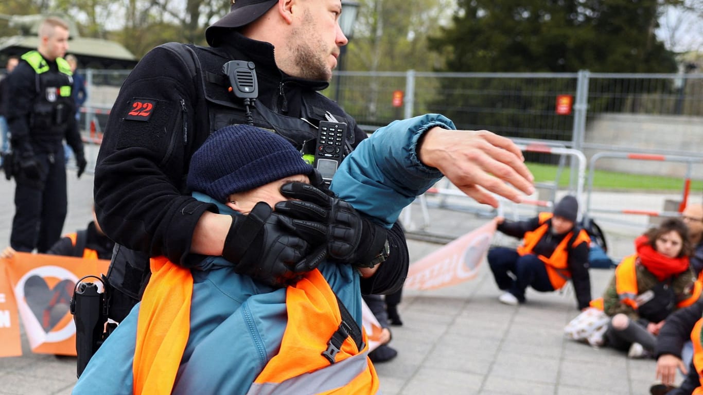 Ein Polizist zieht einen Aktivisten hoch (Symbolbild): Bestimmte Techniken können je nach Umständen eingesetzt werden, sagt die Behörde.