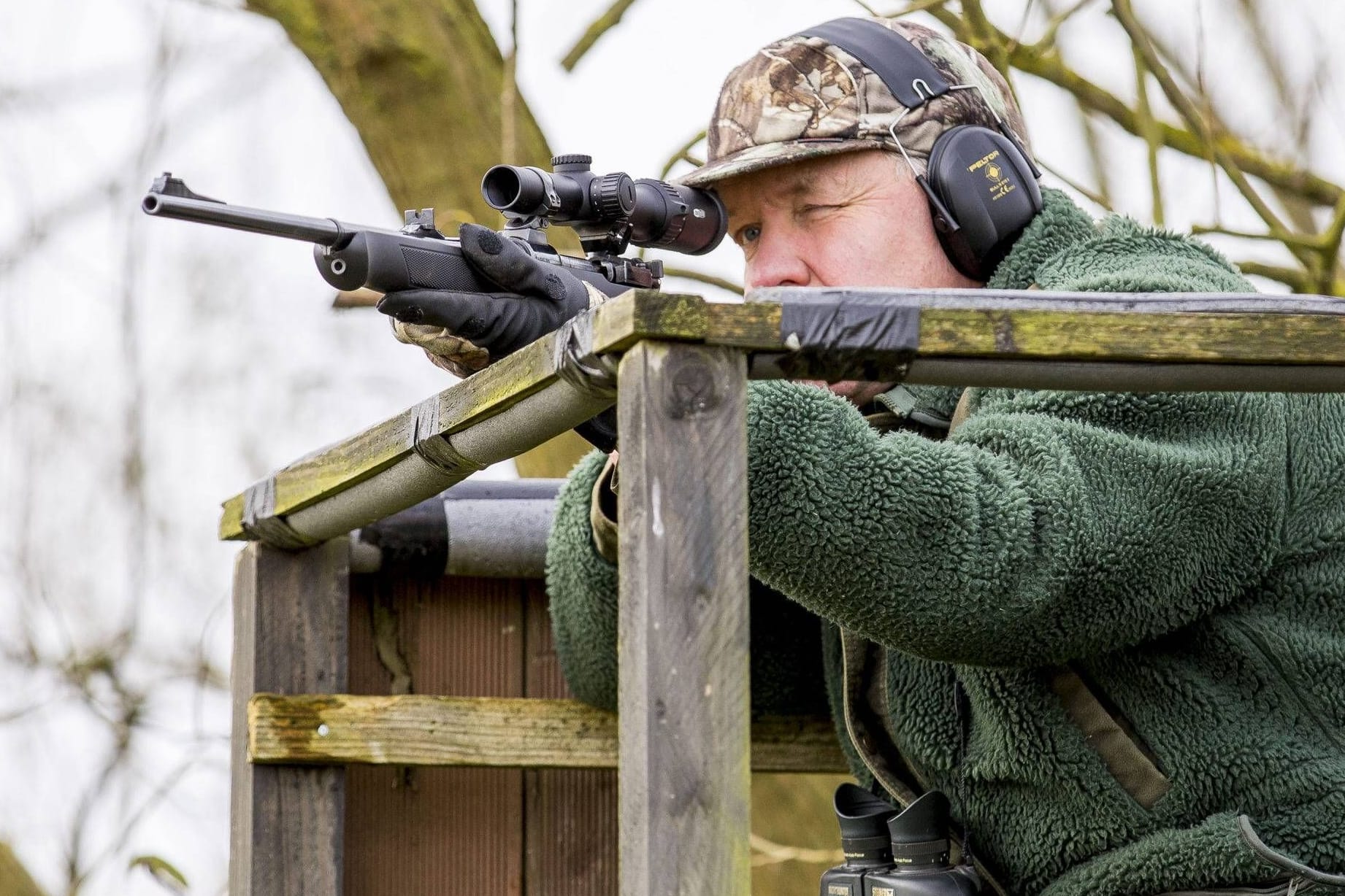 Ein Jäger sitzt mit einem Gewehr auf einem Hochsitz (Symbolbild): Ob Wölfe und Bären geschossen werden oder sich ungehindert ausbreiten sollen, ist umstritten.