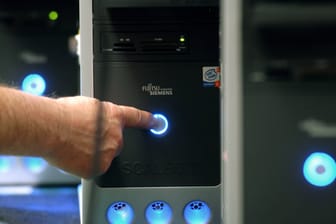 Ein Mann schaltet einen Computer ein: Der Stromverbrauch am PC lässt sich durch einfache Tricks reduzieren.