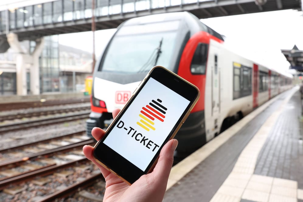 Ein Smartphone mit dem Deutschlandticket vor einem Zug (Symbolfoto): In Niedersachsen sind keine landesweiten Ermäßigungen zum Start des 49-Euro-Tickets angekündigt.