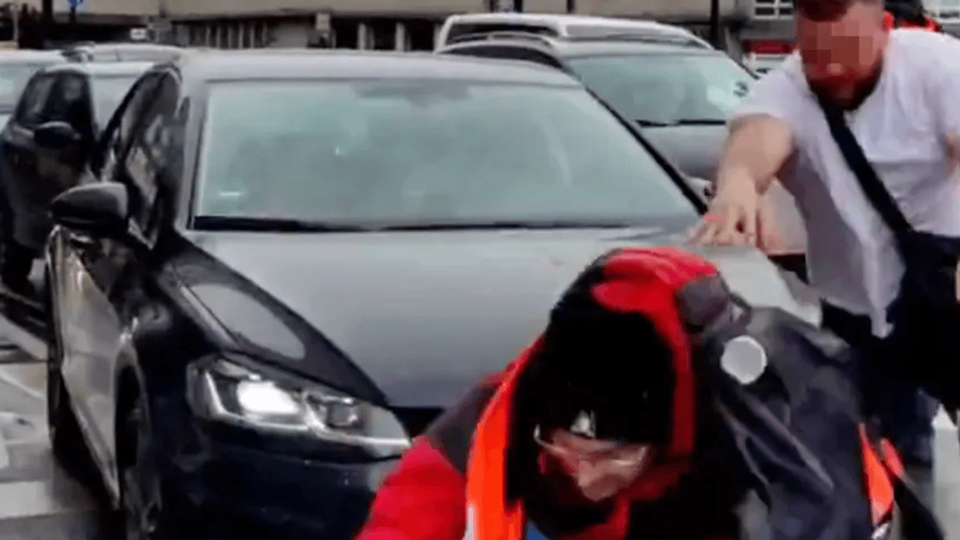 Aktion der "Letzten Generation": Ein Klimaaktivist wird von einem Autofahrer von der Straße gestoßen.