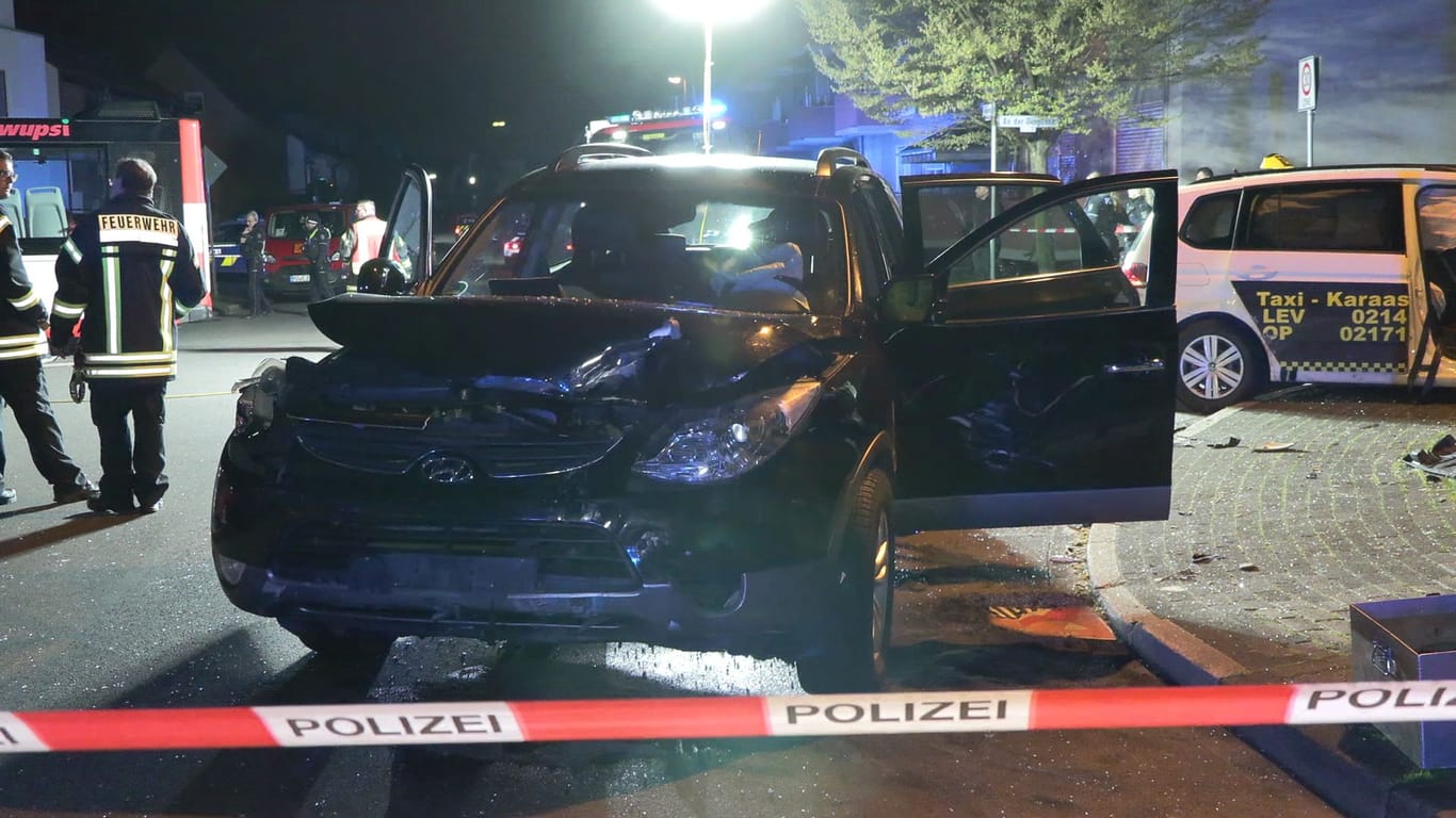 Der beschädigte SUV steht hinter einer Polizeiabsperrung: Bei einem Unfall in Leverkusen wurden zehn Personen verletzt.
