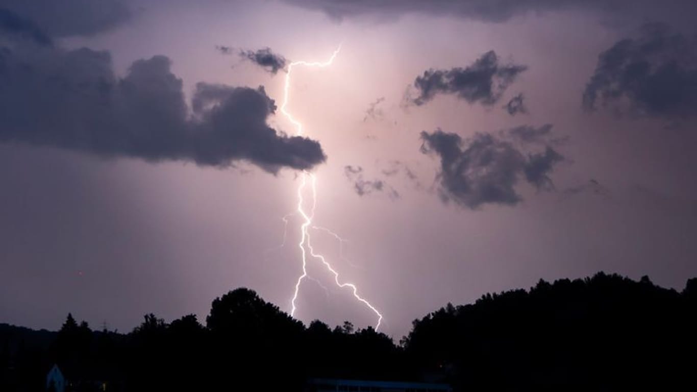 Ein Blitz erhellt den Nachthimmel (Symbolbild): In NRW kommt es zum Wochenbeginn zu Regen und Gewittern.
