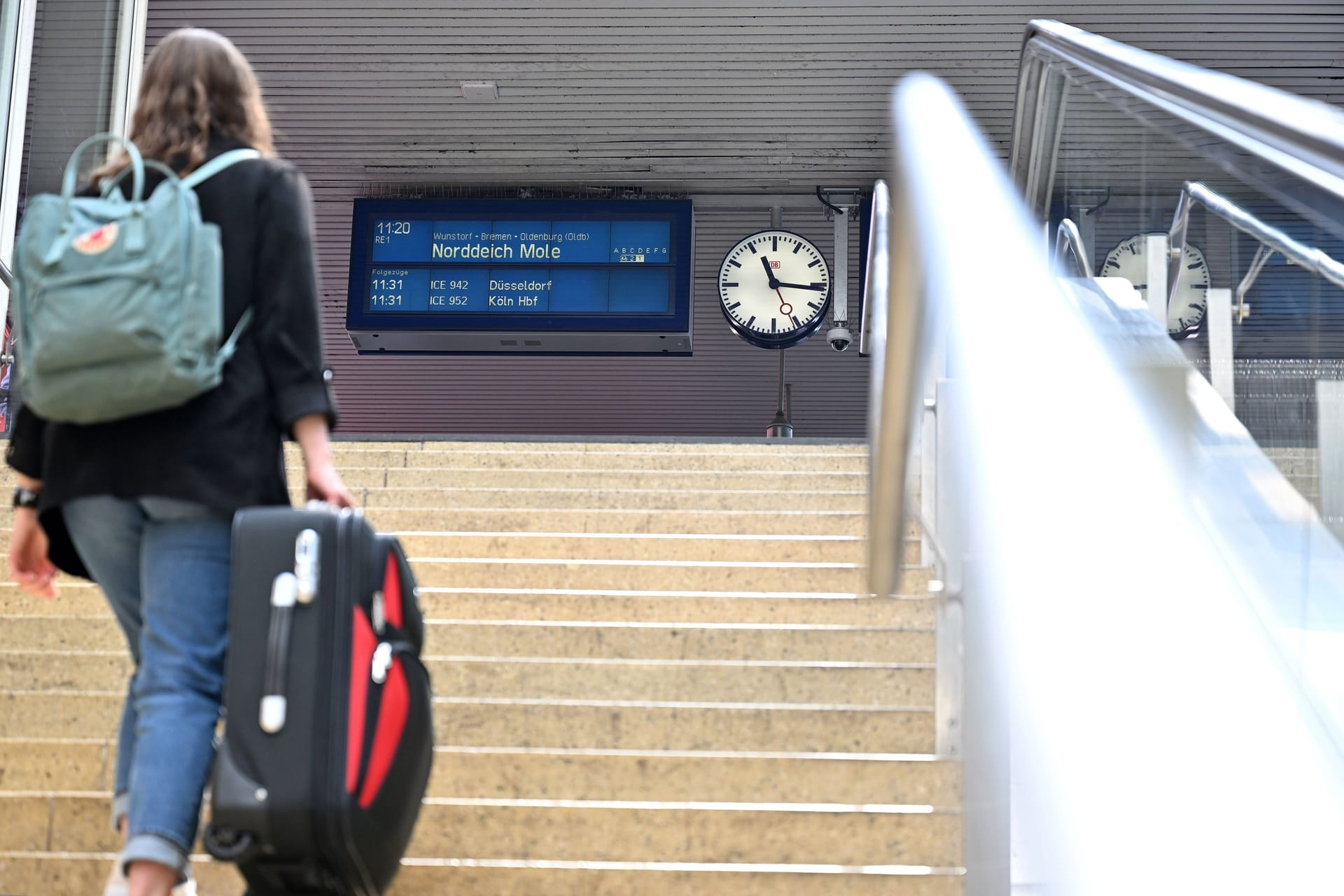 Eine Frau geht mit einem Koffer eine Treppe zum Bahnsteig nach Norddeich Mole hoch (Archivfoto): Bereits 2022 gab es Diskussionen um die Strecke.