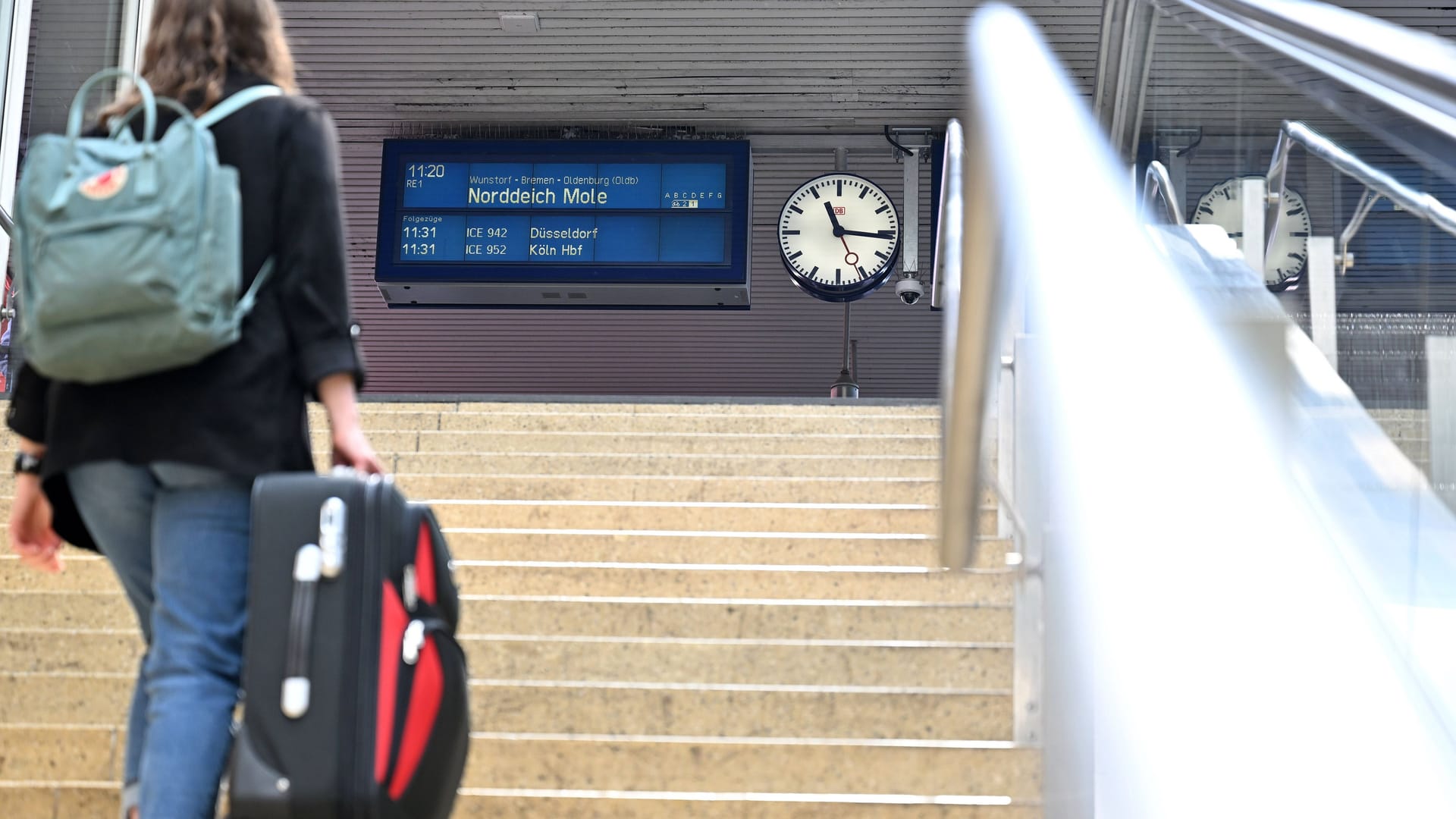 Eine Frau geht mit einem Koffer eine Treppe zum Bahnsteig nach Norddeich Mole hoch (Archivfoto): Bereits 2022 gab es Diskussionen um die Strecke.