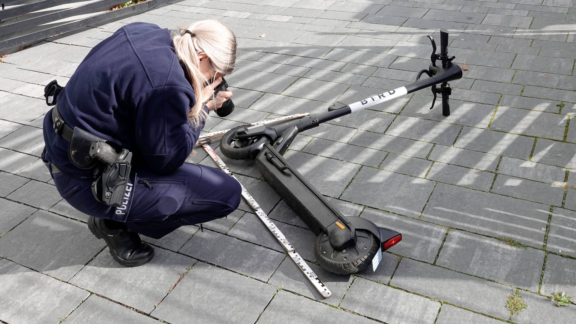 Eine Polizistin fotografiert einen E-Scooter (Symbolfoto): Der Mann war mit einem solchen Gefährt auf dem Gehweg unterwegs, als er vom Auto erfasst wurde, teilte die Polizei mit. Eine Polizistin fotografiert einen E-Scooter (Symbolfoto): Der Mann war mit einem solchen Gefährt auf dem Gehweg unterwegs, als er vom Auto erfasst wurde, teilte die Polizei mit.