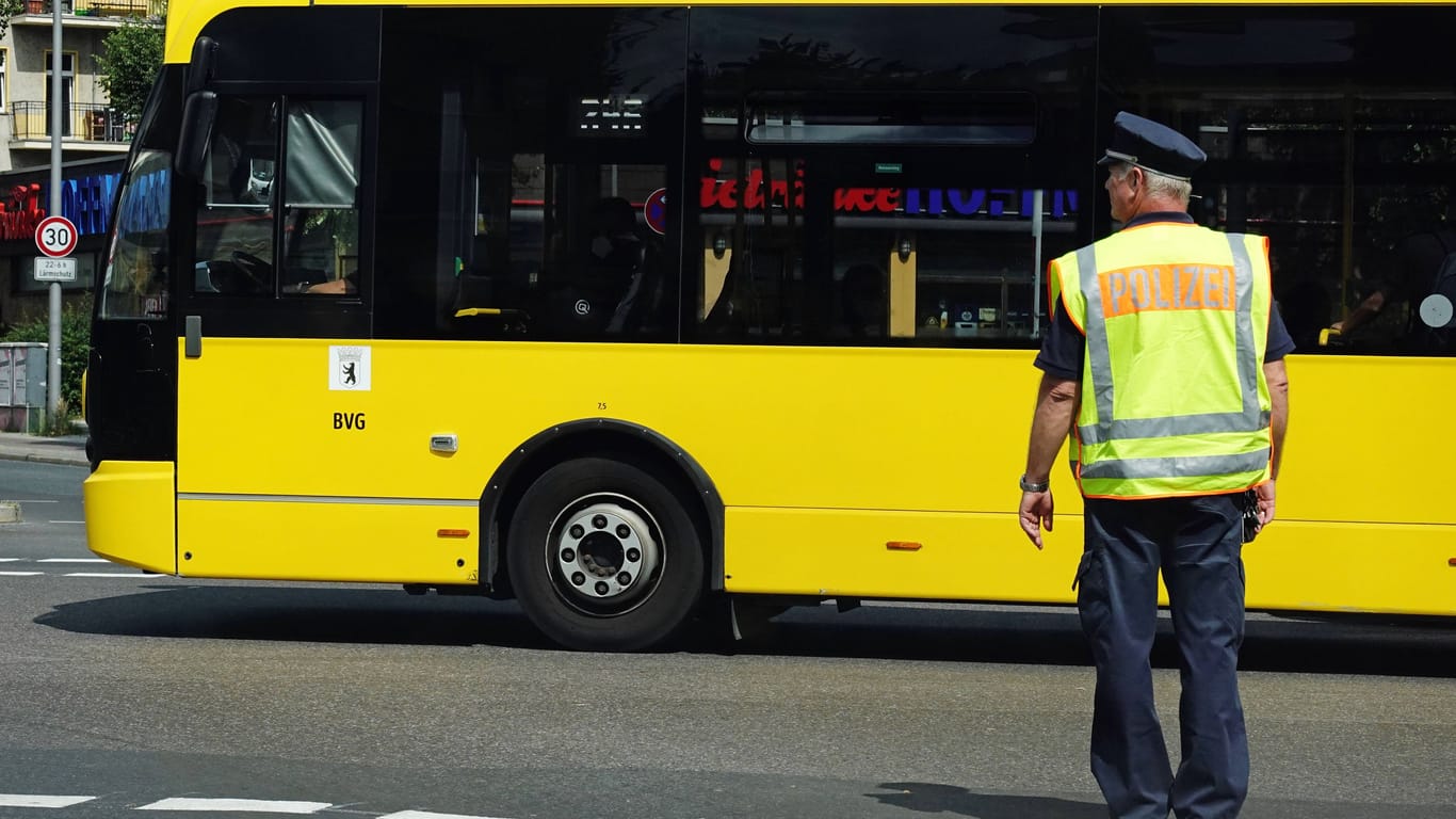 Ein Polizist steht in Warnweste vor einem Bus (Archivbild): Es gibt neue Details zu dem Angriff auf eine Mutter in einem Berliner Bus.