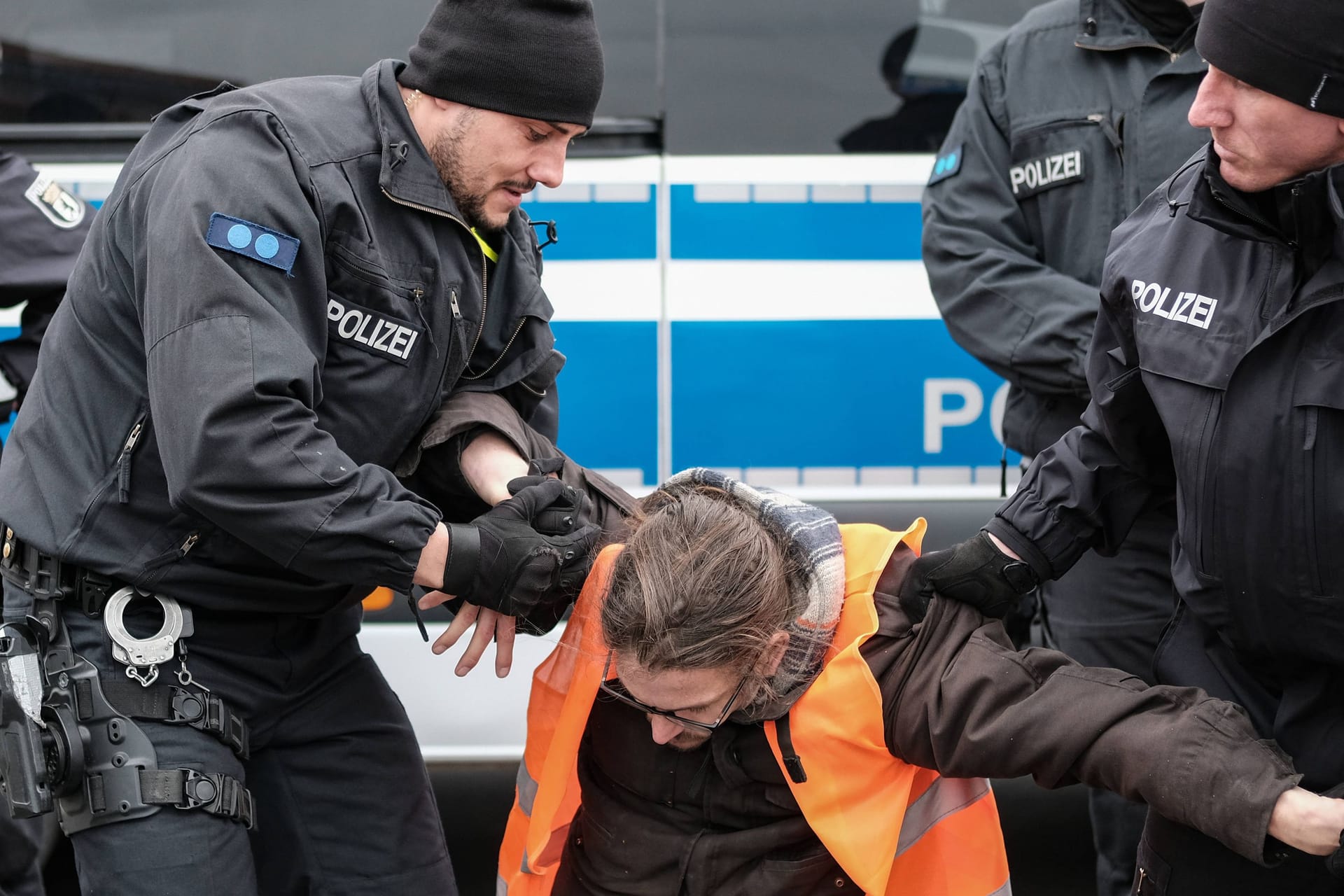 Polizisten tragen Klimaaktivisten weg (Symbolbild): Ein kursierendes Video zeigt Polizeigewalt – doch war sie gerechtfertigt?