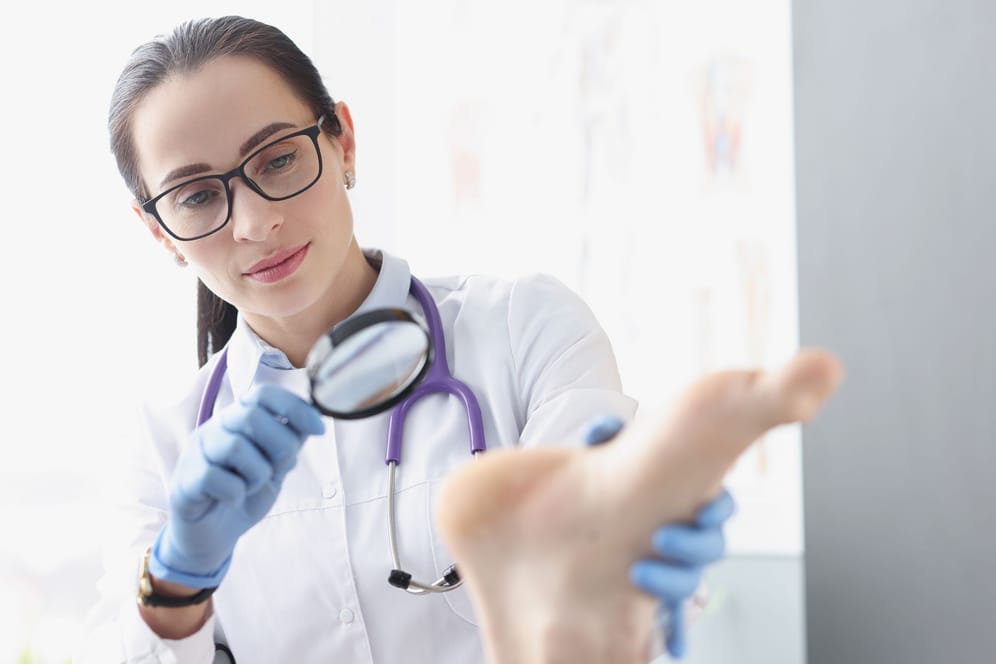 Ärztin untersucht den Fuß einer Person.