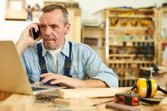 Älterer Handwerker am Telefon (Symbolbild): Eine baldige Rente kann es rechtfertigen, dass ältere Arbeitnehmer weniger Geld erhalten.