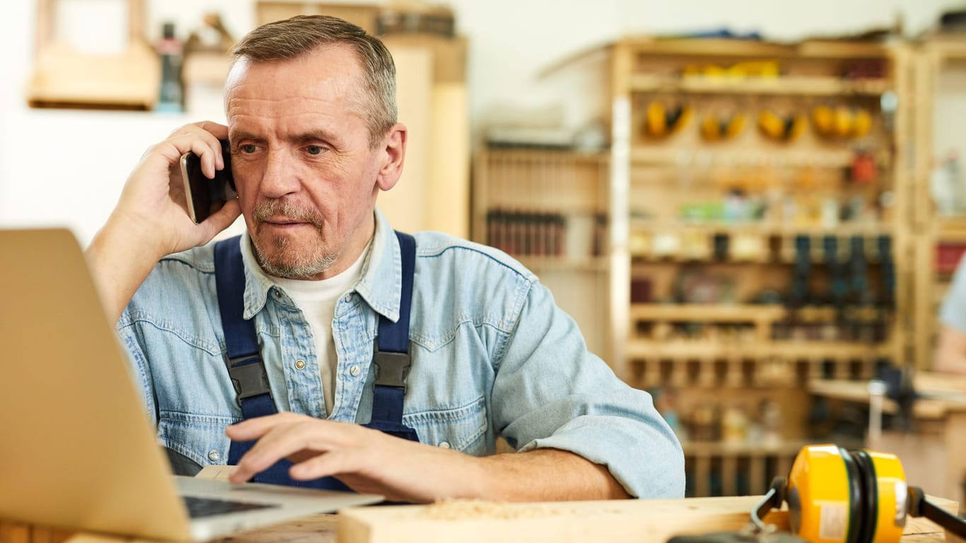 Älterer Handwerker am Telefon (Symbolbild): Eine baldige Rente kann es rechtfertigen, dass ältere Arbeitnehmer weniger Geld erhalten.