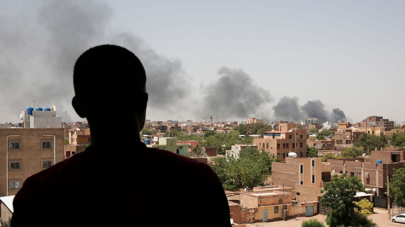 Ein Mann blickt auf die Stadt Khartum: Infolge von Kämpfen steigt schwarzer Rauch auf.