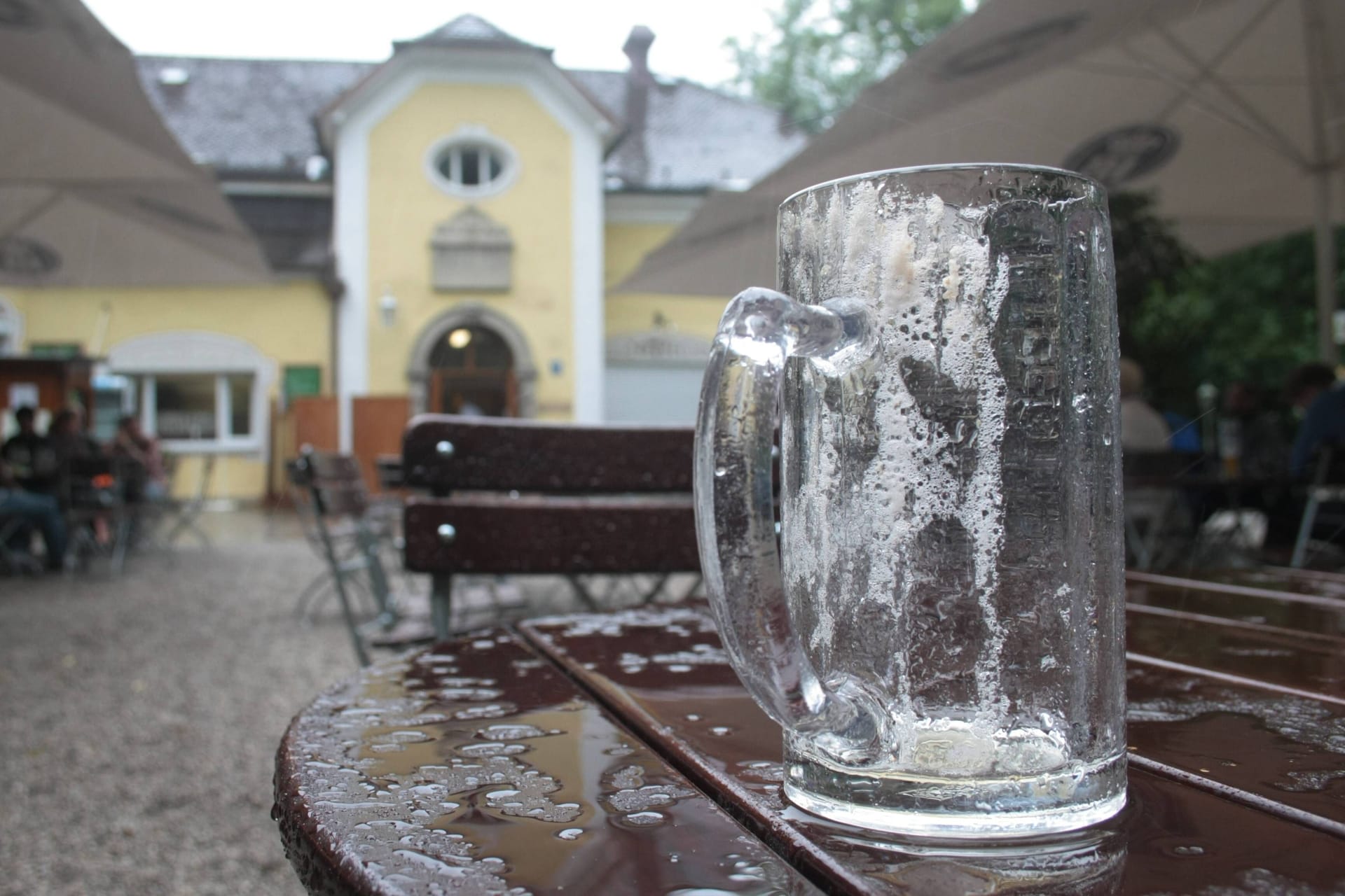 Ein leeres Bierglas auf einem regennassen Tisch in einem Münchner Biergarten (Symbolbild): Am Montag treten Beschäftigte in bayerischen Brauereien in Streik.