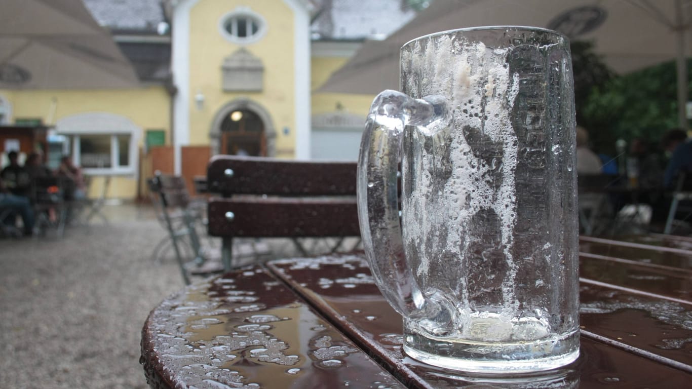 Ein leeres Bierglas auf einem regennassen Tisch in einem Münchner Biergarten (Symbolbild): Am Montag treten Beschäftigte in bayerischen Brauereien in Streik.