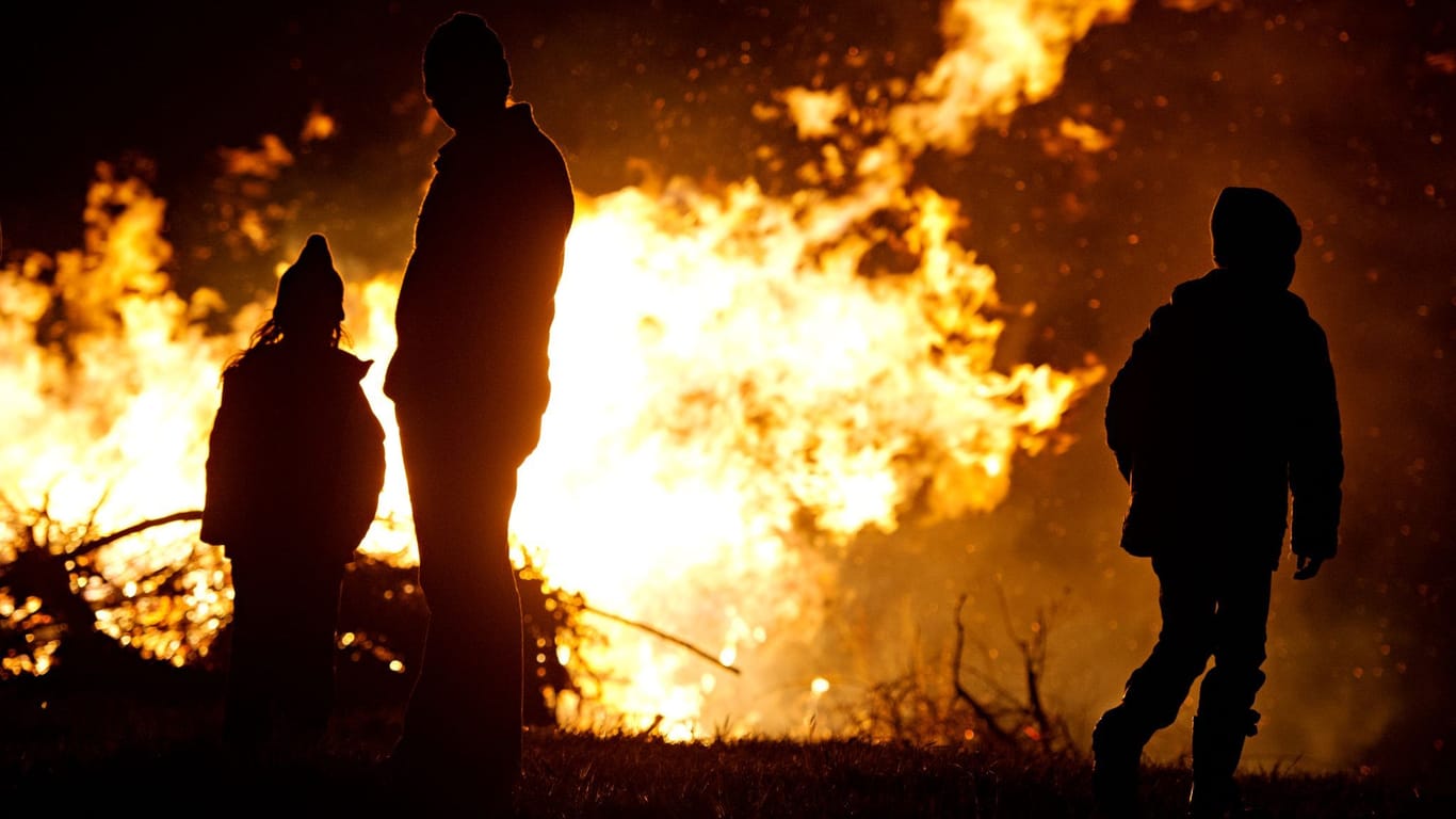 Ein Mann und zwei Kinder sind vor einem Osterfeuer zu sehen (Symbolfoto): "Weiße Ostern wird es definitiv nicht geben", so ein Experte des DWD.