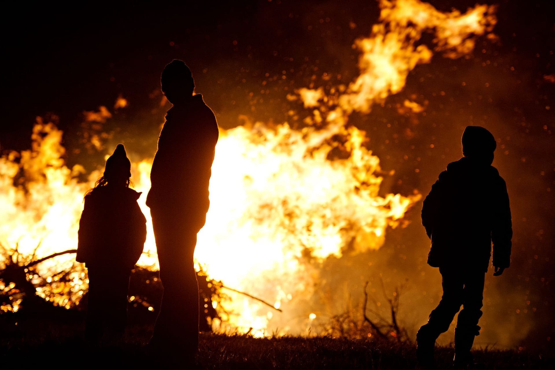 Ein Mann und zwei Kinder sind vor einem Osterfeuer zu sehen (Symbolfoto): "Weiße Ostern wird es definitiv nicht geben", so ein Experte des DWD.