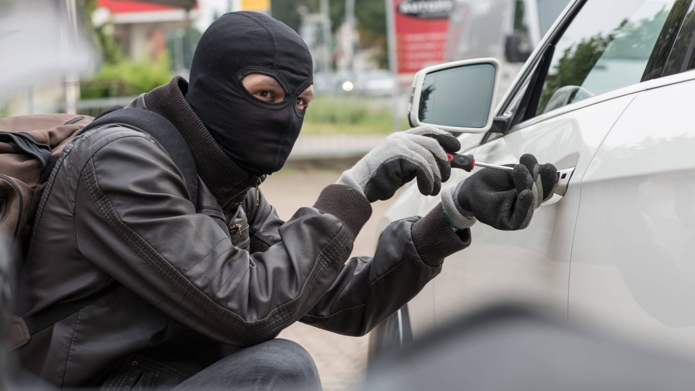 Ein Mann versucht ein Auto aufzubrechen (Symbolfoto): Die gestohlenen Wagen verschifften die Verdächtigen laut Polizei über den Hamburger Hafen.