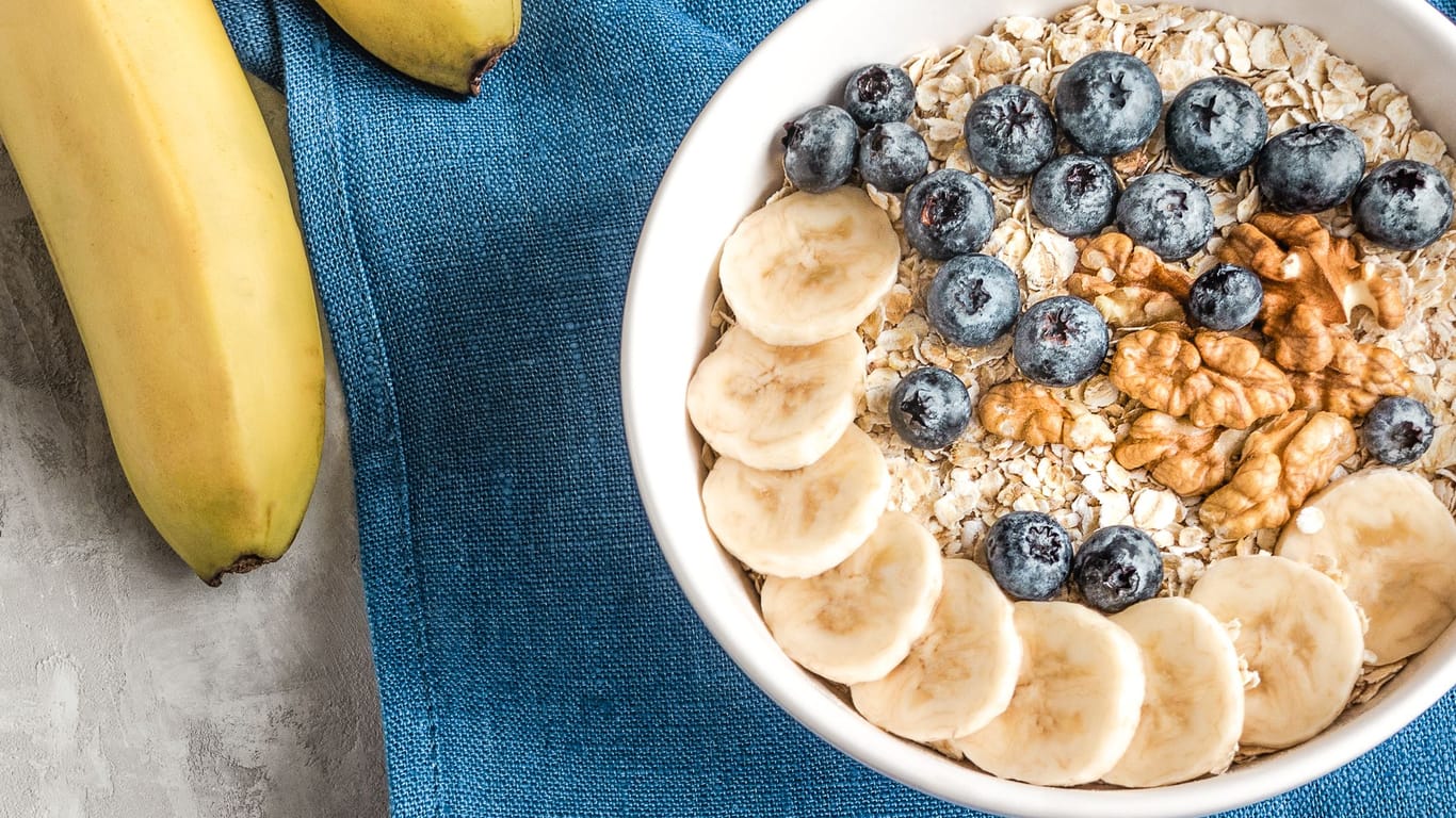 Oat flakes, banana slices, walnuts and blueberries in a bowl