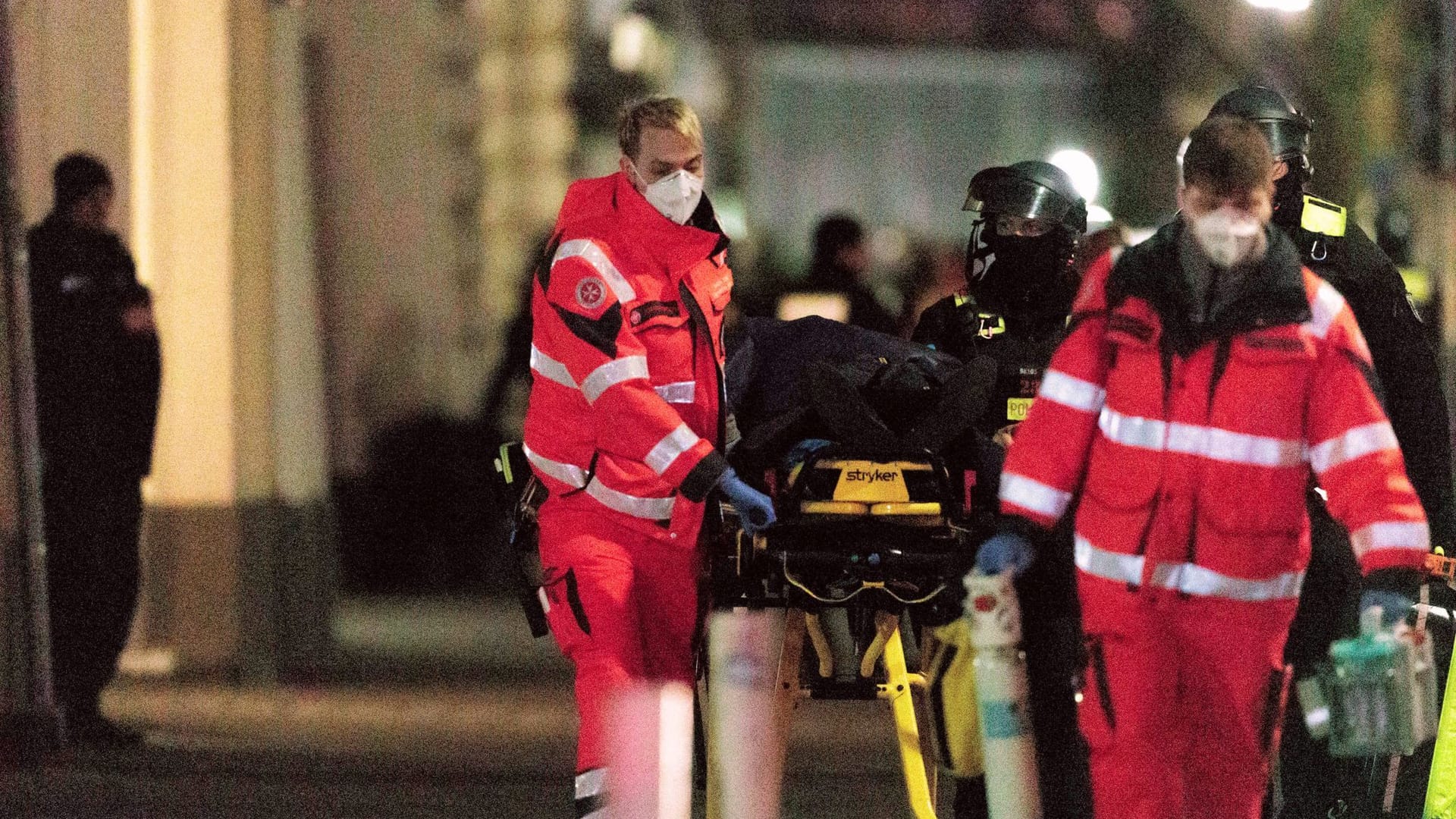 Polizisten in voller Montur und Rettungssanitäter schieben eine Trage mit der unverletzten Geisel zum Krankenwagen. Polizisten in voller Montur und Rettungssanitäter schieben eine Trage mit der unverletzten Geisel zum Krankenwagen.