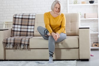 Frau mit Fußschmerzen: Zunehmendes Alter geht mit körperlichen Veränderungen einher, die eine Plantarfasziitis begünstigen können.