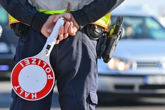 Ein Polizist hält eine Winkerkelle in den Händen (Symbolbild): Im Landkreis Hildesheim musste ein 28-Jähriger seinen Weg statt mit dem Auto zu Fuß fortsetzen.