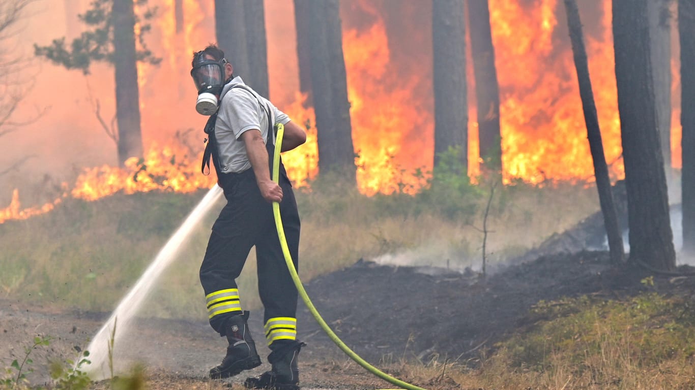 Feuerwehrmann kämpft gegen Waldbrand im Sommer 2022: Dürre und Hitze nehmen durch die Klimakrise zu – damit steigt das Risiko für verheerende Feuer in den Wäldern.
