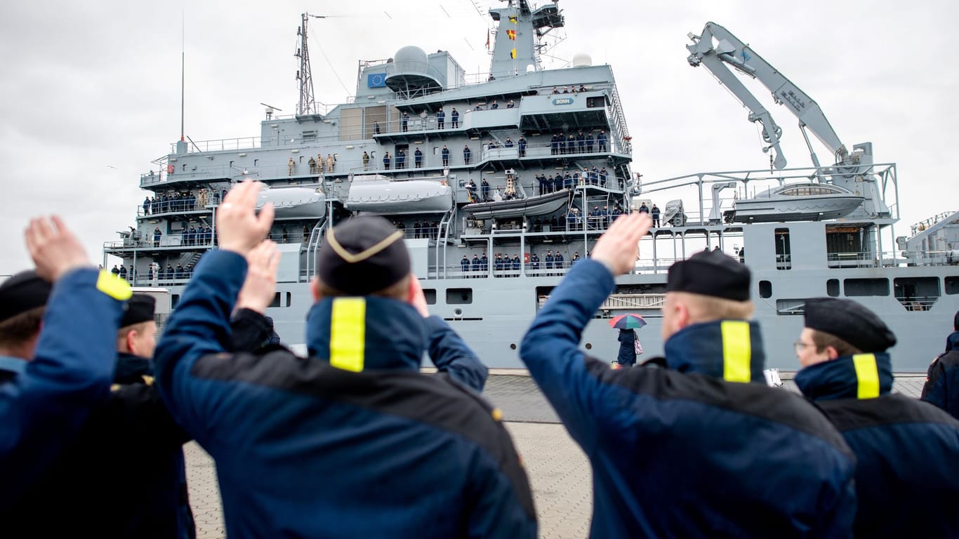 Marinesoldaten winken ihren Kameradinnen und Kameraden an Bord des Einsatzgruppenversorgers "Bonn" im Hafen am Marinestützpunkt kurz vor dem Ablegen zu.