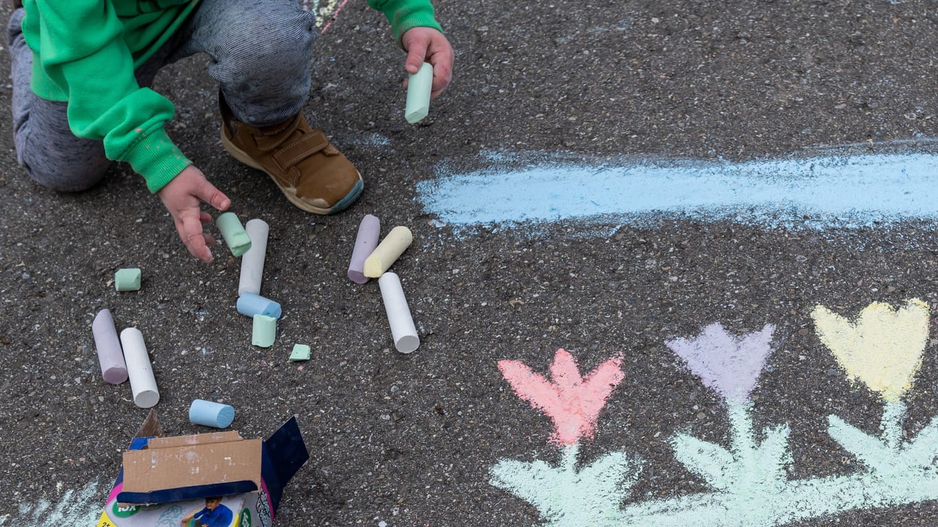 Ein Kind malt auf einer Straße mit Malkreide (Archivbild): Kitas in Niedersachsen bleiben belastet – ist das Hilfspaket gescheitert?