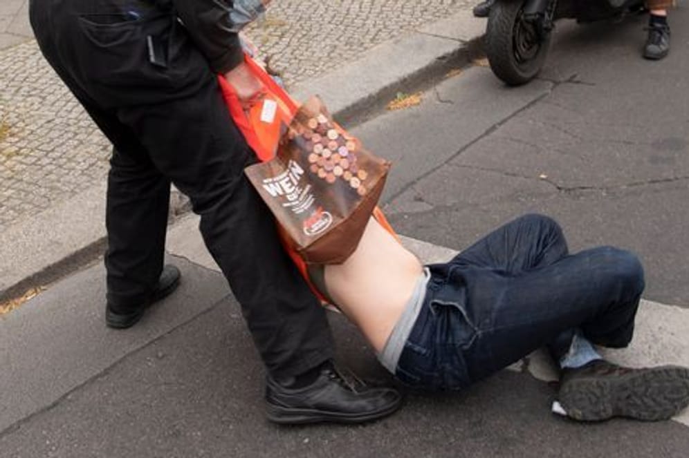 Ein Mann zieht einen Klimaaktivisten von der Straße: In Berlin blockierten die Aktivisten am Freitag wieder.