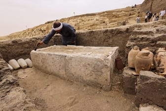 Ein Arbeiter reinigt eines der Steinbetten in einer Mumienwerkstatt, die jetzt nahe Kairo entdeckt wurde.
