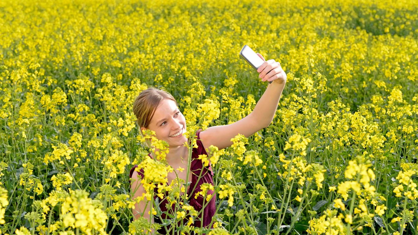 Eine Frau schießt ein Selfie von sich im Raps, Rapsfeld.