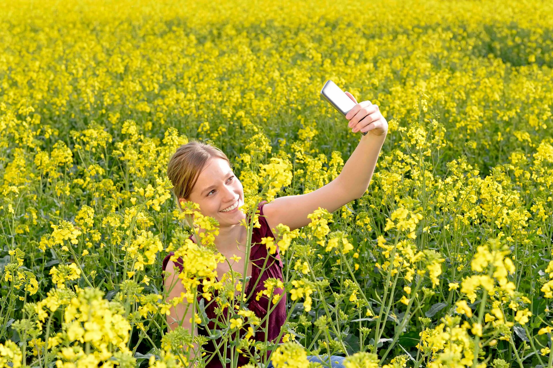 Eine Frau schießt ein Selfie von sich im Raps, Rapsfeld.