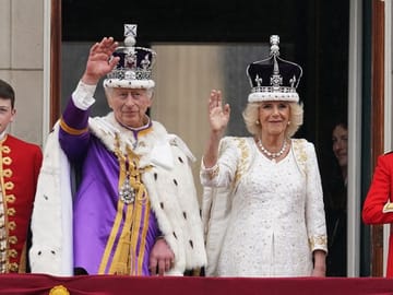 The newly crowned King Charles III.  and Queen Camilla wave to the crowd from the balcony of Buckingham Palace.