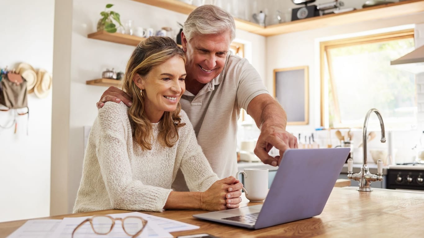 Rentnerpaar blickt freudig auf ein Laptop (Symbolbild): Mit etwas Wissen können Sie sich Ihre Altersvorsorge selber bauen.