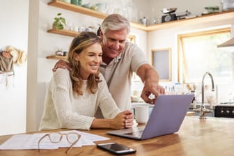 Rentnerpaar blickt freudig auf ein Laptop (Symbolbild): Mit etwas Wissen können Sie sich Ihre Altersvorsorge selber bauen.