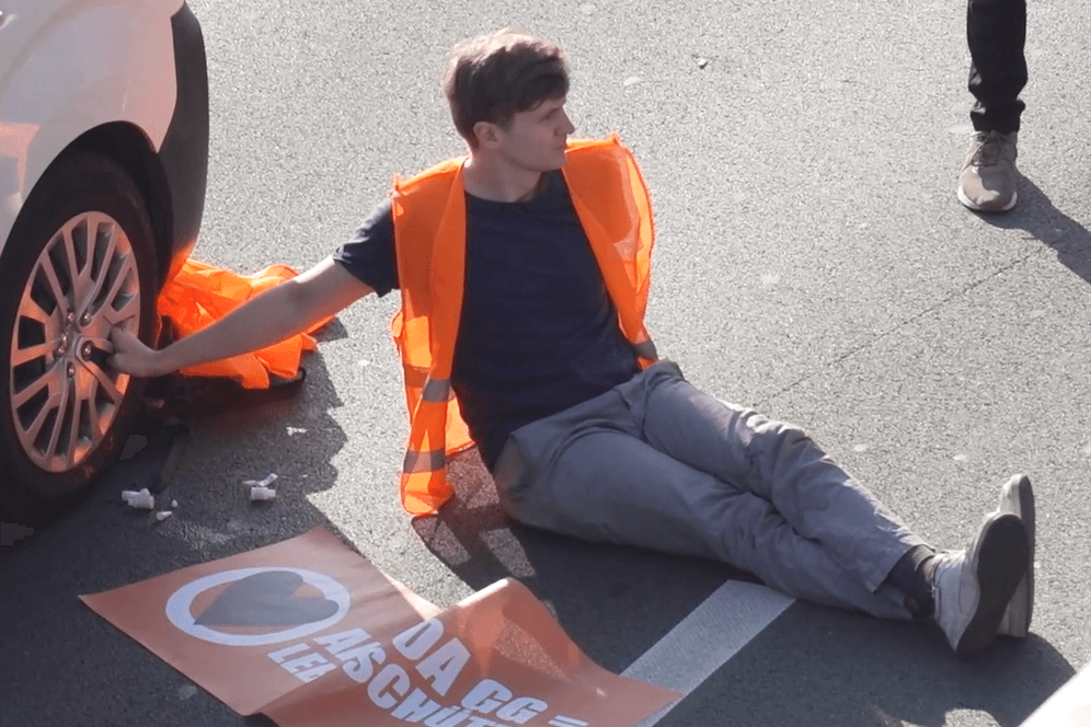 Ein Aktivist klebte an einem Autoreifen: An zahlreichen Orten in Berlin blockierte die "Letzte Generation" Straßen.