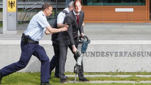 Klimaprotest in Karlsruhe: Ein als Olaf Scholz verkleideter Klimaaktivist der Gruppierung "Letzte Generation" wird von Sicherheitskräften abgeführt.