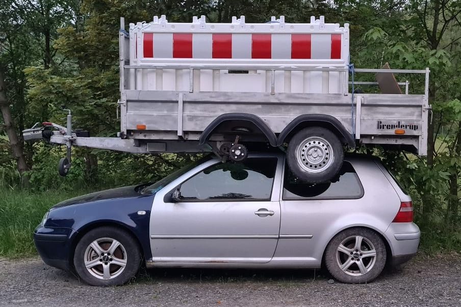 Das beschädigte Auto samt Anhänger: Wie ist er auf das Dach gekommen?